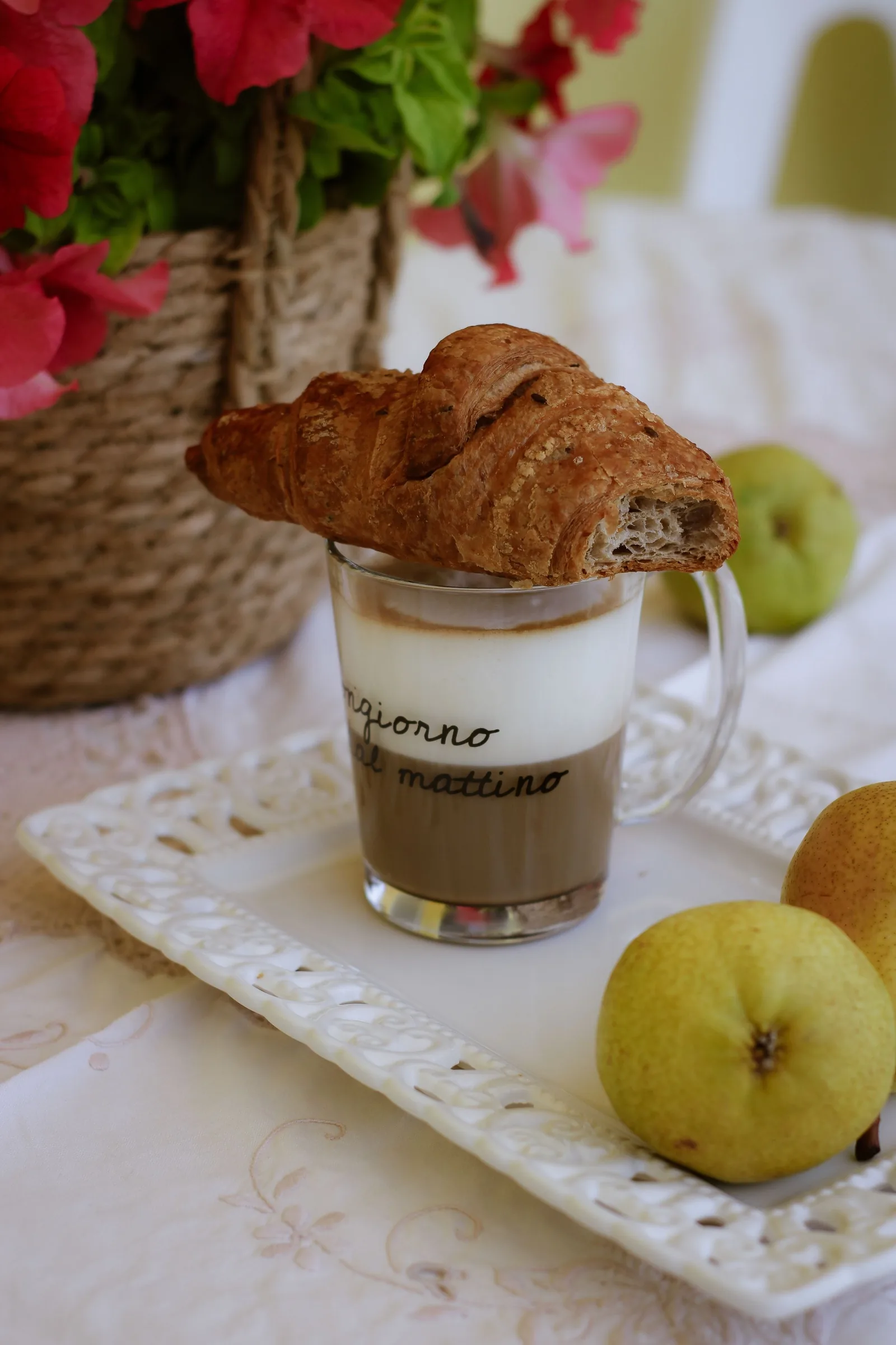 Croissant on a glass of milky coffee with pears