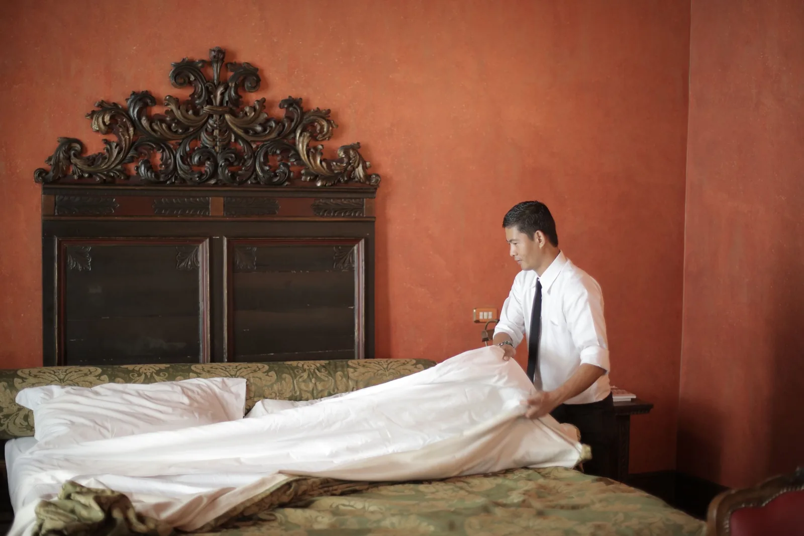 Host making a bed in a red room