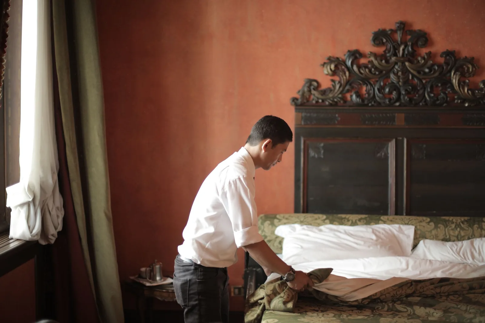 Housekeeper smoothing white sheets